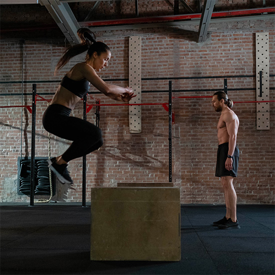 Dans la salle de Crossfit Kasadenn, une femme et un homme sautent sur des box